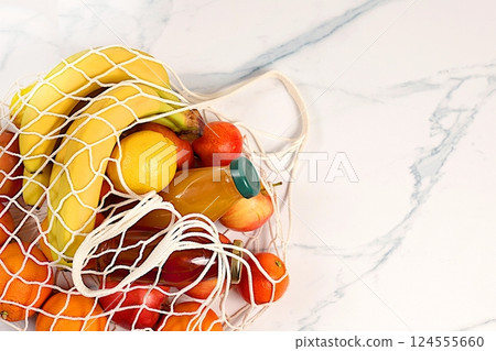 Fabric shopping bag with healthy vegan products for weight loss. Lemons, oranges, tomatoes, apples, bananas and natural juice in a reusable bag, food delivery concept, store advertising Fabric shopping bag with healthy vegan products for weight loss. Lemons, oranges, tomatoes, apples, bananas and natural juice in a reusable bag, food delivery concept, store advertising 124555660