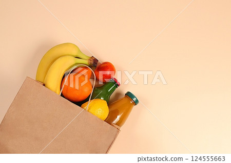 Paper eco bag with healthy vegan products for weight loss. Lemons, oranges, tomatoes, apples, bananas and natural juice in a craft bag, food delivery concept, store advertising Paper eco bag with healthy vegan products for weight loss. Lemons, oranges, tomatoes, apples, bananas and natural juice in a craft bag, food delivery concept, store advertising 124555663