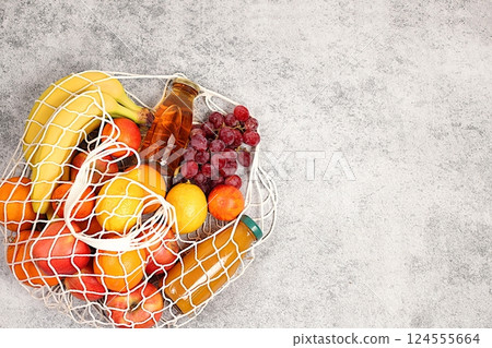 Lemons, oranges, tomatoes, apples, bananas, grapes and natural juice in a reusable bag, Fabric string bag with healthy vegan products for weight loss. food delivery concept, store advertising Lemons, oranges, tomatoes, apples, bananas, grapes and natural juice in a reusable bag, Fabric string bag with healthy vegan products for weight loss. food delivery concept, store advertising 124555664