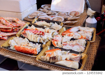 Cooked and cracked king crab legs with tender white meat are arranged in plastic trays 124555842