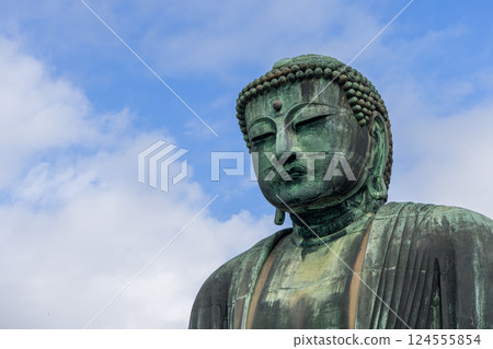Serene face of the Kamakura Buddha framed by soft clouds with weathered bronze textures Serene face of the Kamakura Buddha framed by soft clouds with weathered bronze textures 124555854