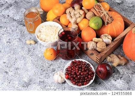Healthy natural food for the flu and colds. Selection of fresh fruits and vegetables with vitamin C, tangerines, cabbage, cranberries, cinnamon, honey on a concrete table. Organic virus protection Healthy natural food for the flu and colds. Selection of fresh fruits and vegetables with vitamin C, tangerines, cabbage, cranberries, cinnamon, honey on a concrete table. Organic virus protection 124555868