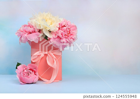 Delicate flowers of peonies and roses in a pink gift box. Abstract flower arrangement, concept of gifts for a holiday, birthday, wedding and mother's day. Spring still life and banner for the screen 124555948