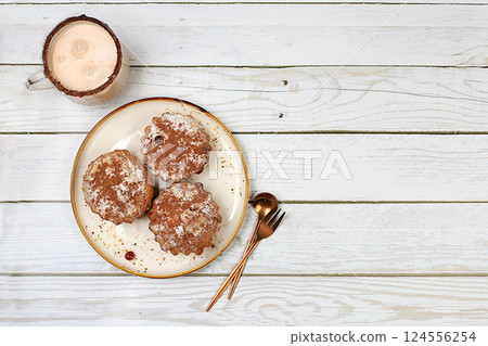 Delicious chocolate muffins with cranberries and milk drink eggnog with cocoa on a wooden table. Advertising card or menu for a cafe, restaurant. Concept of a modern bakery, selective focus Delicious chocolate muffins with cranberries and milk drink eggnog with cocoa on a wooden table. Advertising card or menu for a cafe, restaurant. Concept of a modern bakery, selective focus 124556254