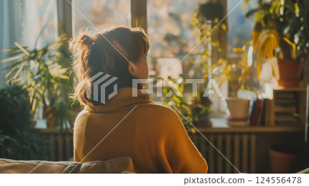 Woman gazing out a sunny window, reflective. 124556478