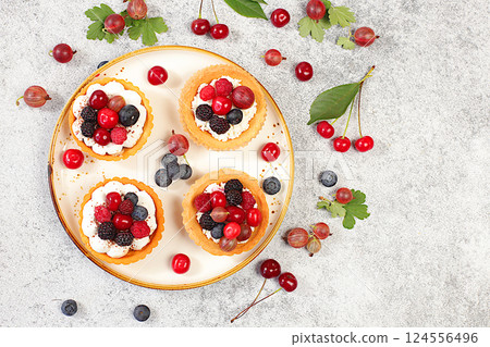 Delicious tartlets with fresh berries raspberries, cherries, gooseberries and blueberries. Cupcakes with soft curd cream, summer dessert. Concept of a modern bakery, advertising for a cafe, Delicious tartlets with fresh berries raspberries, cherries, gooseberries and blueberries. Cupcakes with soft curd cream, summer dessert. Concept of a modern bakery, advertising for a cafe, 124556496