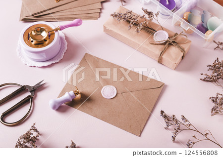 Craft envelope with wax seal and crafting items on pink 124556808