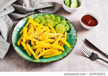 A plate of delicious French fries with cucumber and ketchup on the table A plate of delicious French fries with cucumber and ketchup on the table 124556822