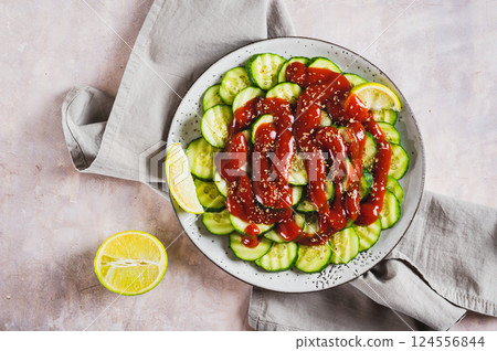 Close up of mexican spicy cucumbers with chili sauce and lime on a plate on the table top view Close up of mexican spicy cucumbers with chili sauce and lime on a plate on the table top view 124556844