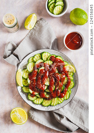 Delicious cucumbers with chili pepper and lime on a plate on the table top and vertical view 124556845