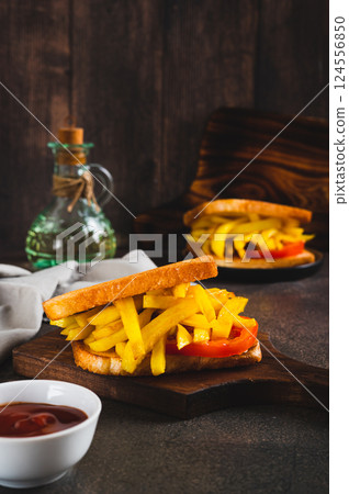 Fried toasts with french fries and tomato on a board on the table vertical view Fried toasts with french fries and tomato on a board on the table vertical view 124556850