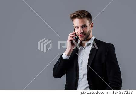 confident businessman use smartphone. boss male with mobile phone. sexy ceo on gray background. modern office life. charismatic business owner. stylish broker. handsome man in suit. copy space 124557238