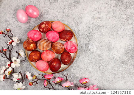 Easter celebration concept, marbled Easter eggs painted with onion peel and pink matcha on concrete background with sakura branches, ideas for homemade Easter preparations,. Easter celebration concept, marbled Easter eggs painted with onion peel and pink matcha on concrete background with sakura branches, ideas for homemade Easter preparations,. 124557318