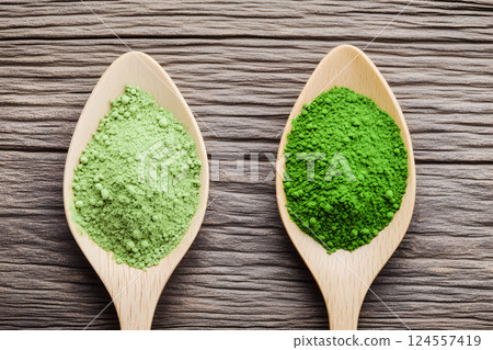 Green and light green spirulina and chlorella powders displayed on wooden spoons showcasing their vibrant colors and textures in a well-lit kitchen setting 124557419