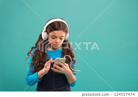 schoolgirl use digital device. casual fashion for kids. kid long hair listen music in headset. small child make play list on smartphone. small girl use mp3 player. study in modern life. copy space 124557474