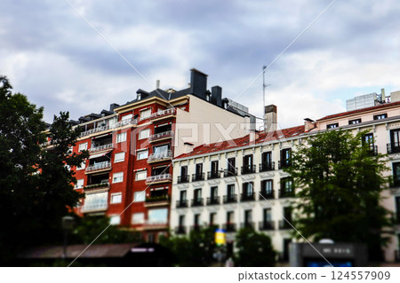 Facades of red and white old buildings on a city street of a metropolis. Historical architecture on European street. Travel postcard. Urban landscape. 124557909