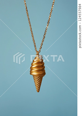 Elegant golden ice cream cone necklace on a light blue background. White gold ice cream cone jewelry pendant. Sweets and fast fashion concept. Rip diet, creative jewelry. Summer vibes, holidays. 124557984