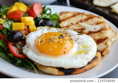 A plate featuring a sunny side up egg with greens, corn, and tomatoes. Delicious breakfast plate with fresh vegetables and fried egg. Healthy breakfast, diet and weight loss theme 124558048