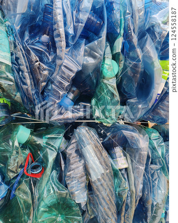 A close-up of baled plastic bottles, crushed and wrapped in blue plastic, showcasing waste recycling efforts. A close-up of baled plastic bottles, crushed and wrapped in blue plastic, showcasing waste recycling efforts. 124558187