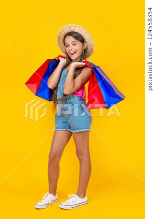 happy teen child shopper with shopping bags on yellow background. full length 124558354
