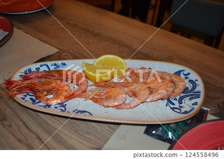 Spanish seafood meal with fresh shrimp and lemon garnish on rustic plate Spanish seafood meal with fresh shrimp and lemon garnish on rustic plate 124558496