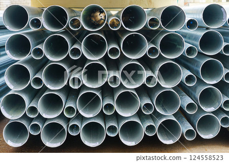 A stack of new tall conical metal lamp posts on wooden pallets at a infrastructure construction site 124558523