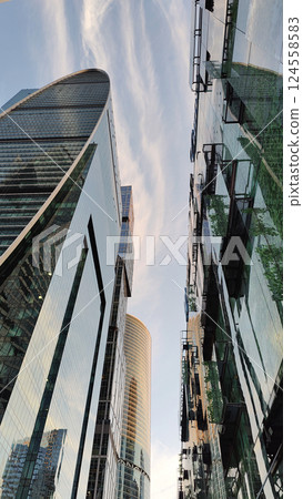 A cityscape featuring modern high-rise buildings with reflective glass facades, capturing the warm hues of sunset. A cityscape featuring modern high-rise buildings with reflective glass facades, capturing the warm hues of sunset. 124558583