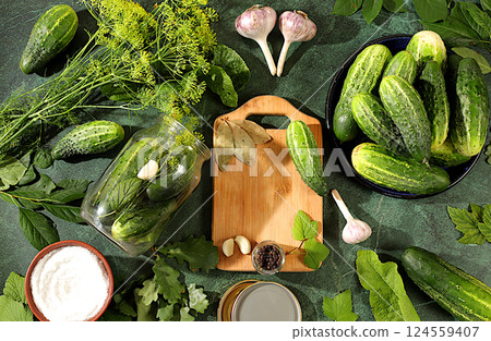 Fresh cucumbers in a jar, spices, garlic and leaves on a concrete kitchen table, homemade pickling recipe, village harvest, cucumbers and ingredients for pickling, home canning concept,.. 124559407