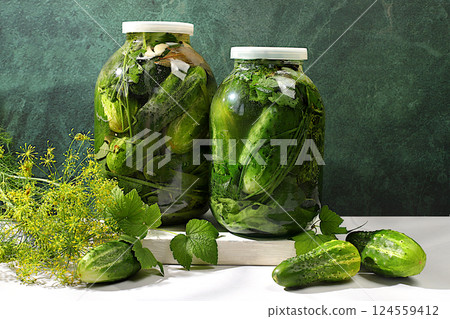 Pickled cucumbers in a jar with garlic and dill on the kitchen table, village harvest, homemade pickling recipe, cucumbers and ingredients for pickling, home canning concept, healthy and natural food. 124559412