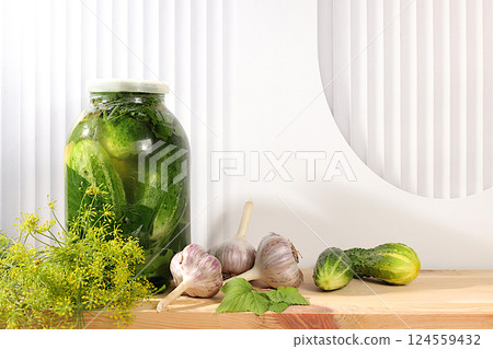 Pickled cucumbers in a jar with garlic and dill on a wooden kitchen table, rustic harvest, homemade pickling recipe, cucumbers and ingredients for pickling, home canning concept, 124559432