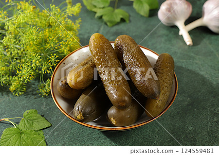 Fresh pickled cucumbers in a bowl with garlic and dill on a concrete table, village harvest, homemade pickling recipe, cucumbers and ingredients for pickling, home canning concept, 124559481