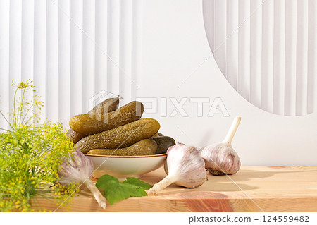 Fresh pickled cucumbers in a bowl with garlic and dill on the kitchen table, village harvest, homemade pickling recipe, cucumbers and ingredients for pickling, home canning concept, 124559482