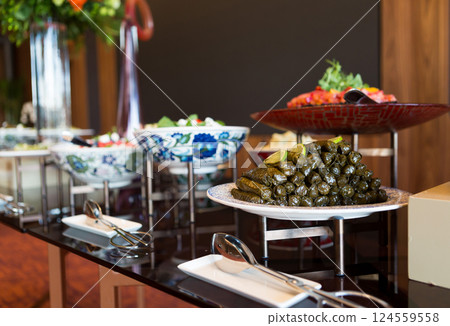 A beautifully arranged long table filled with a rich variety of Turkish cuisine, set for a festive banquet or celebration, adorned with elegant floral decorations, Turkey 124559558