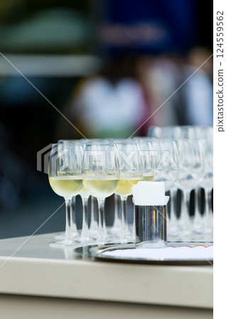 A tray of elegantly arranged wine glasses, each half filled and glistening, ready to be served. 124559562