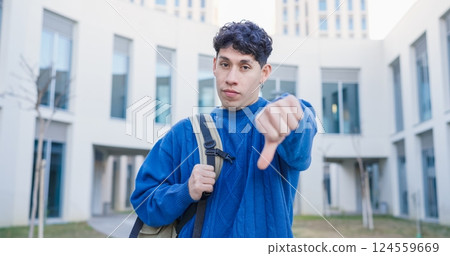 University student showing thumbs down gesture of disapproval University student showing thumbs down gesture of disapproval 124559669