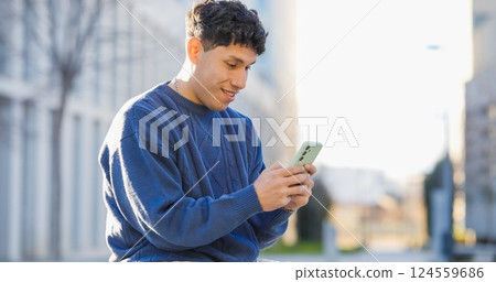 Young latin american man using smartphone in urban setting 124559686