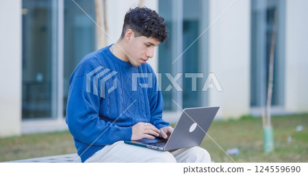 Young hispanic student working with laptop, sitting on bench in university campus Young hispanic student working with laptop, sitting on bench in university campus 124559690