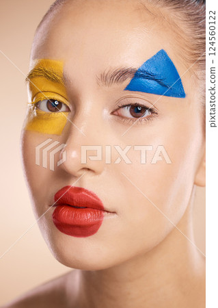 Makeup, clown and face of a woman with color for creative, cosmetic and fantasy against a studio background. Halloween, circus and portrait of a model with facial paint for art and crazy creativity 124560122