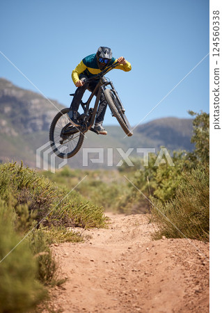Bike, bmx and fitness with a man biker on a dirt trail or track taking a jump with a mountain bike. Sky, nature and cycling with a mountain biker jumping in midair while riding outdoor for adrenaline Bike, bmx and fitness with a man biker on a dirt trail or track taking a jump with a mountain bike. Sky, nature and cycling with a mountain biker jumping in midair while riding outdoor for adrenaline 124560338