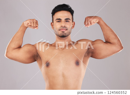 Fitness, portrait and man flexing muscle on gray studio background. Sports, wellness and proud Indian body builder showing biceps, power and arm strength during training, exercise or body workout. Fitness, portrait and man flexing muscle on gray studio background. Sports, wellness and proud Indian body builder showing biceps, power and arm strength during training, exercise or body workout. 124560352