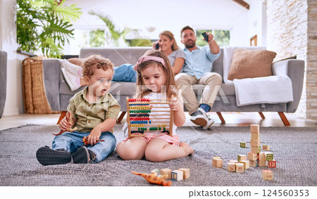 Development, family and children with math toys and playing with building blocks in the house living room. Education, mother and relaxed father watching tv with kids or siblings learning from a game 124560353