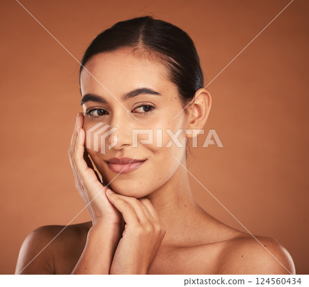 Skincare, beauty and face of latino woman with makeup, cosmetics and healthy skin. Spa, wellness and young girl pose with hands for dermatology, cosmetology and facial in studio on brown background 124560434