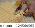 Close up square sheet of dough cut into strips with woman's hands on wooden board. Cutter, flour, egg on kitchen table. Home cooking baking puffs 124560565