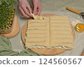 Woman's hands twists dough strips on wooden board. Cutter, egg, green towel, microgreens sprouts on kitchen table. Home cooking baking puffs 124560567