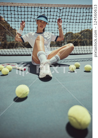 Relax, portrait and tennis woman at net on exercise, fitness and court break at sports ground. Training, workout and cardio of professional athlete club girl resting on floor with tennis balls. 124560613