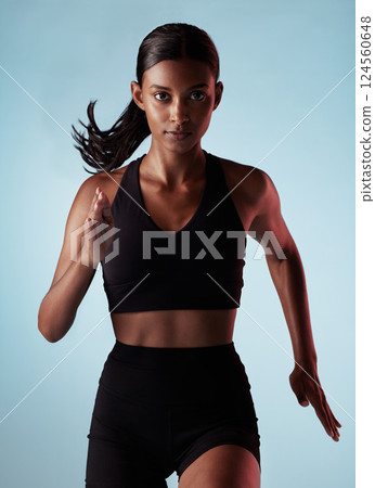Fitness, running and energy with portrait of woman training in studio for health, power and endurance. Stamina, sprinting and cardio with runner for sports, workout and exercise in blue background 124560648