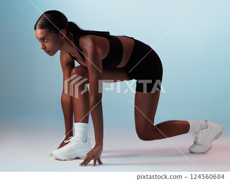Start position, runner and fitness woman in studio ready for marathon, exercise or cardio workout. Motivation, run and athlete or model from India doing sports training isolated by a blue background. 124560684