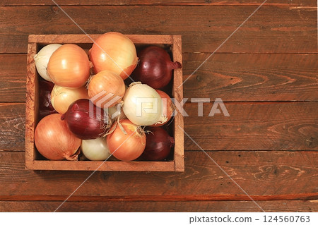 Various varieties of onions in a box on a wooden background, autumn harvest concept, red, white and golden onions for breeding in agriculture, selective focus Various varieties of onions in a box on a wooden background, autumn harvest concept, red, white and golden onions for breeding in agriculture, selective focus 124560763