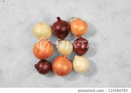 Various varieties of onions on a gray concrete background, the concept of harvesting in autumn, red, white and golden onions for breeding in agriculture, selective focus Various varieties of onions on a gray concrete background, the concept of harvesting in autumn, red, white and golden onions for breeding in agriculture, selective focus 124560765