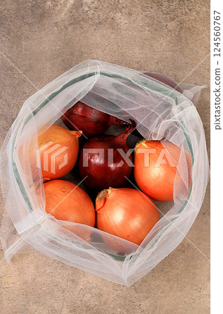 Various varieties of onions in fabric packaging. Healthy natural products in an eco bag to boost immunity, healthy lifestyle concept, zero waste. Banner for the store. No plastic. Selective focus Various varieties of onions in fabric packaging. Healthy natural products in an eco bag to boost immunity, healthy lifestyle concept, zero waste. Banner for the store. No plastic. Selective focus 124560767